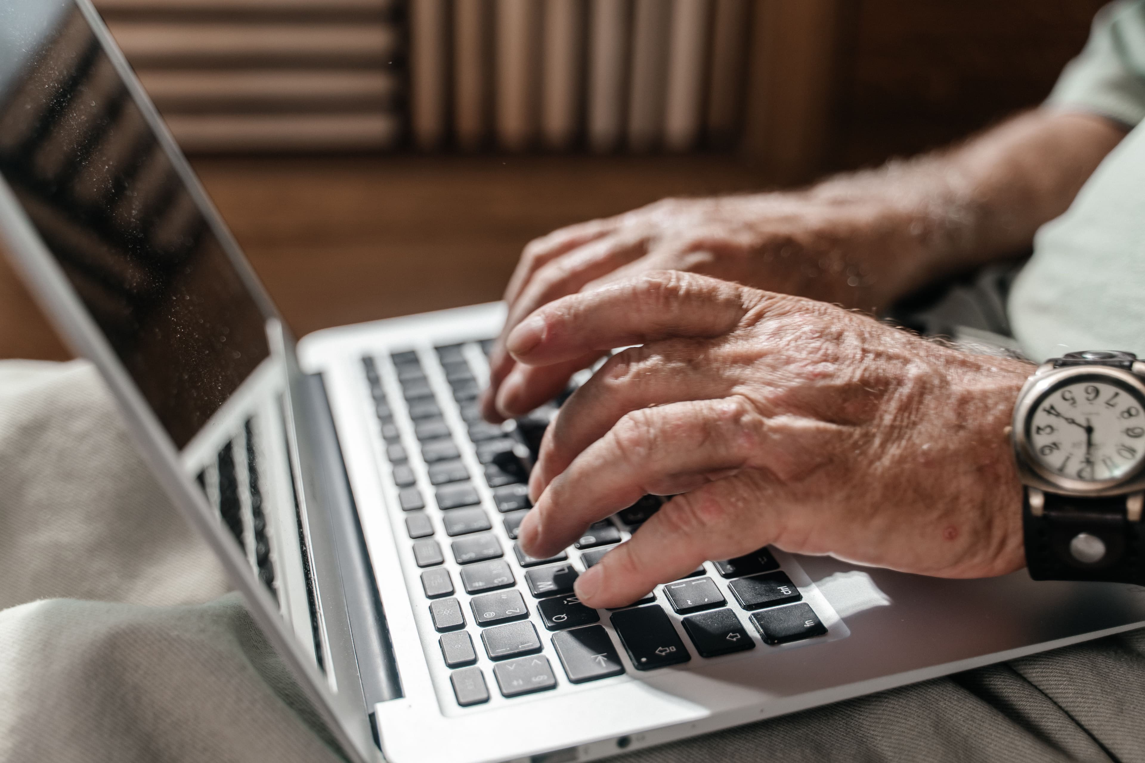Older man typing on a laptop, ordering his prescription medication safely from a registered online pharmacy.